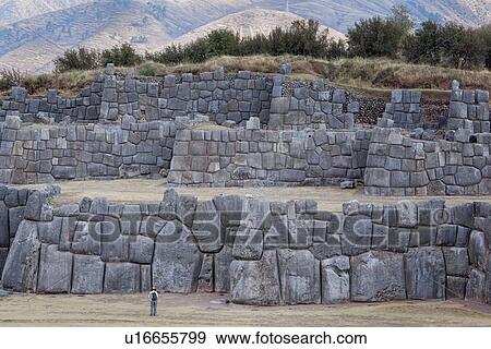 Sacsaywaman Inca ruins: view of the massive zig zag stone wall fortifications in late afternoon sunlight with tourist in foreground, Sacred Valley, Cuzco, Peru View Large Photo Image Stock Photo - Sacsaywaman Inca ruins: view of the massive zig zag stone wall fortifications in late afternoon sunlight with tourist in foreground, Sacred Valley, Cuzco, Peru. Fotosearch