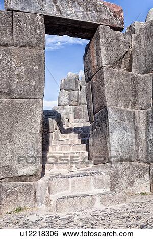 Stock Photograph - Sacsaywaman Inca ruins: view of the massive zig zag stone wall fortifications in late afternoon sunlight with typical trapezoid doorway and stairway, moon rising beyond, Sacred Valley, Cuzco, Peru Sacred Valley, Cuzco, Peru. Fotosearch