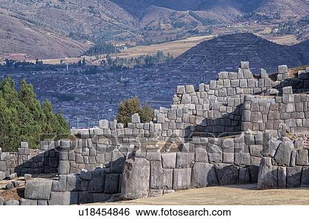 Stock Photograph - Sacsaywaman Inca ruins: view of the massive zig zag stone wall fortifications in late afternoon sunlight, with strong triangular shadows, Sacred Valley, Cuzco, Peru. Fotosearch