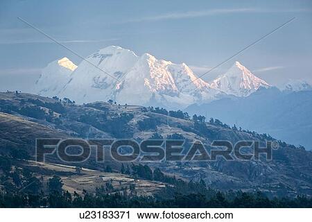 Stock Image - View at sunrise: pinklight on snow-ccovered Huascaran and Cordilleras mountains with hills and valley in foreground, Cordilleras, Peru. Fotosearch