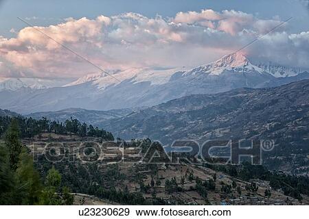 View at sunset: pink clouds and snow-covered Huascaran and Cordilleras mountains with hills and valley in foreground, Cordilleras, Peru View Large Photo Image Stock Photo - View at sunset: pink clouds and snow-covered Huascaran and Cordilleras mountains with hills and valley in foreground, Cordilleras, Peru. Fotosearch