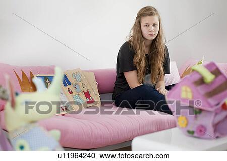 Stock Image - Annoyed preteen girl surrounded by toys. Fotosearch