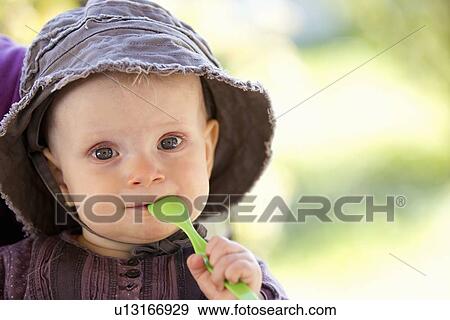 Stock Photo - Baby chewing on spoon outdoors. Fotosearch