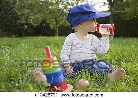 Stock Image - Baby drinking juice in grass. Fotosearch