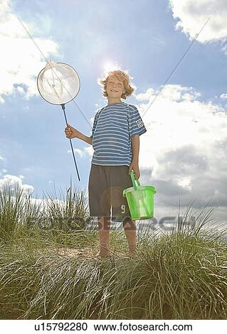Stock Image - Boy carrying net and pail outdoors. Fotosearch