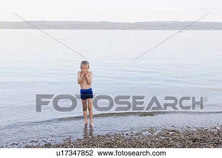 Stock Image - Boy covering his face on beach. Fotosearch