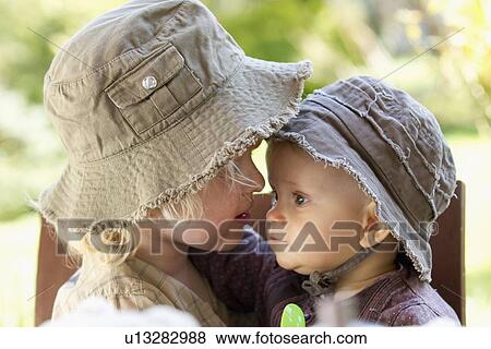 Stock Photo - Boy holding baby sister in chair. Fotosearch
