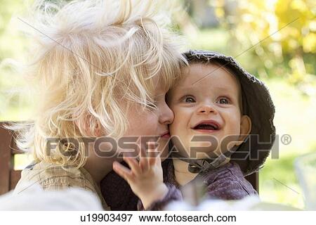 Stock Photo - Boy kissing baby sister at table. Fotosearch