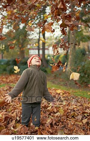 Stock Image - Boy playing in autumn leaves. Fotosearch