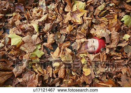 Stock Photo - Boy playing in autumn leaves. Fotosearch