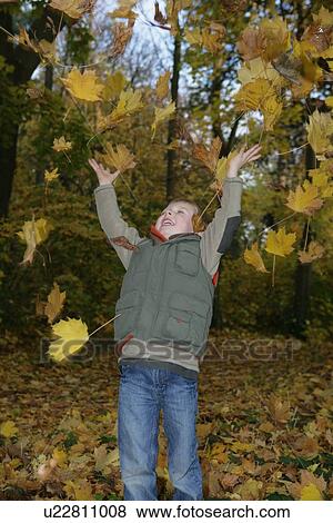 Boy playing in autumn leaves View Large Photo Image Stock Photo - Boy playing in autumn leaves. Fotosearch