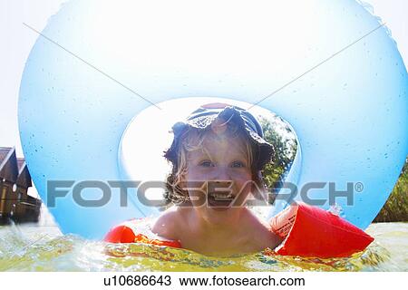 Stock Image - Boy playing with inner tube in pool. Fotosearch