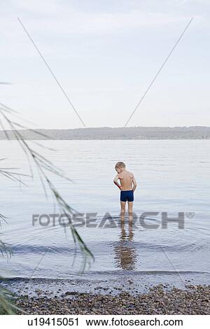 Boy wading on rocky beach View Large Photo Image Stock Image - Boy wading on rocky beach. Fotosearch