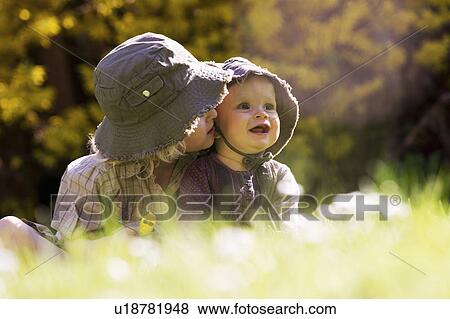 Brother holding baby sister in grass View Large Photo Image Stock Photo - Brother holding baby sister in grass. Fotosearch