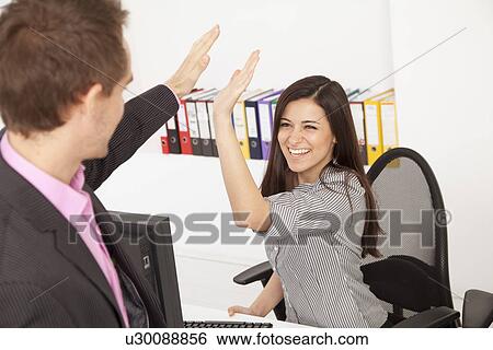 Stock Photograph - Business people high fiving in office. Fotosearch