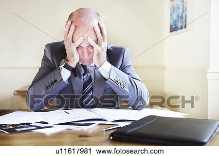 Stock Image - Businessman reading notes at desk. Fotosearch