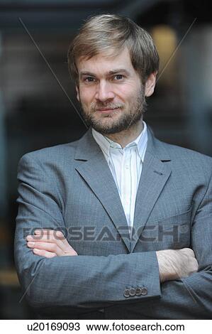 Stock Image - Businessman standing with arms folded. Fotosearch