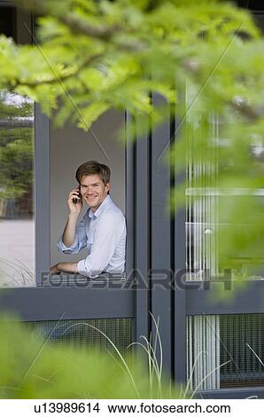 Businessman using cell phone in window View Large Photo Image Picture - Businessman using cell phone in window. Fotosearch