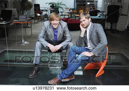 Stock Image - Businessmen sitting together in office. Fotosearch