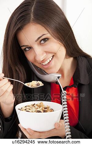 Stock Photography - Businesswoman eating on telephone. Fotosearch