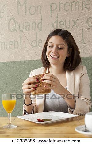 Stock Photograph - Businesswoman eating sandwich in cafe. Fotosearch
