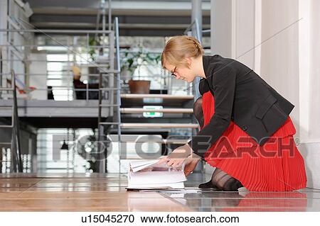Stock Image - Businesswoman reading book on floor. Fotosearch