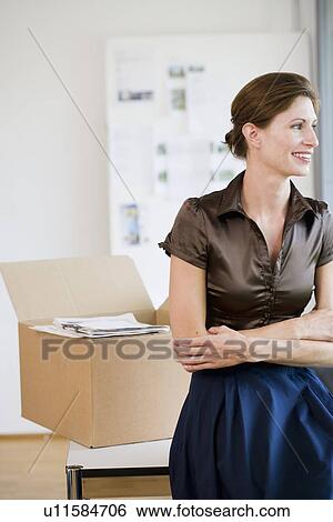 Stock Photograph - Businesswoman sitting on desk in office. Fotosearch