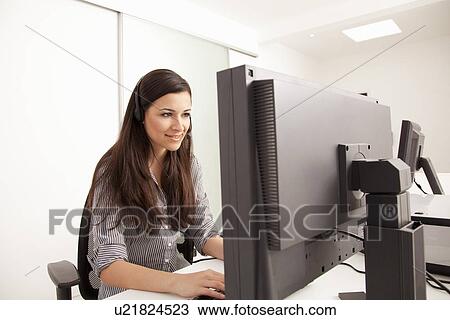 Businesswoman talking on headset at desk View Large Photo Image Stock Image - Businesswoman talking on headset at desk. Fotosearch