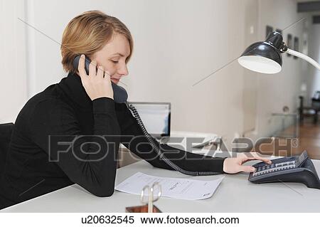 Stock Photography - Businesswoman talking on phone at desk. Fotosearch