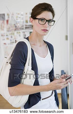 Stock Image - Businesswoman using cell phone in office. Fotosearch