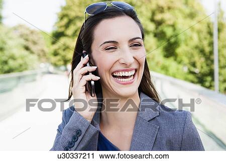 Stock Image - Businesswoman using cell phone outdoors. Fotosearch