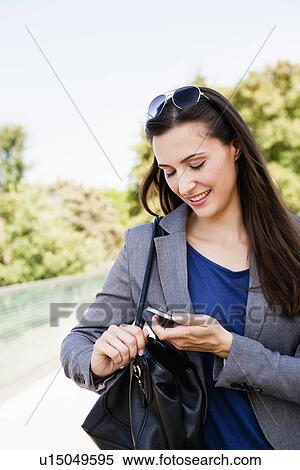 Stock Photography - Businesswoman using cell phone outdoors. Fotosearch