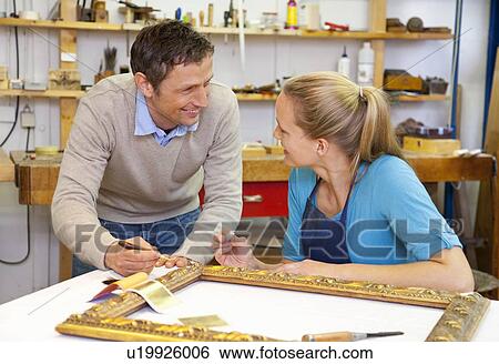 Stock Photograph - Carpenter and assistant working in shop. Fotosearch