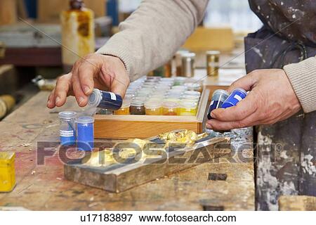 Stock Photo - Carpenter examining jars of pigment. Fotosearch