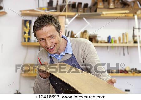 Carpenter examining sheet of wood View Large Photo Image Stock Image - Carpenter examining sheet of wood. Fotosearch
