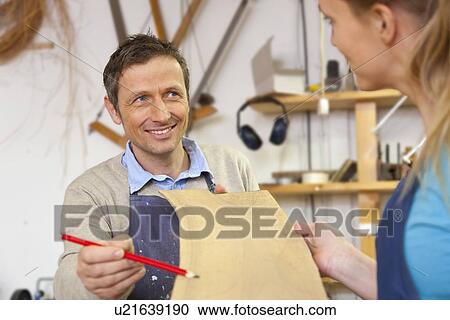 Carpenter giving blueprints to assistant View Large Photo Image Stock Image - Carpenter giving blueprints to assistant. Fotosearch