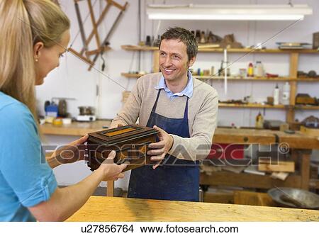 Picture - Carpenter giving jewelry box to client. Fotosearch