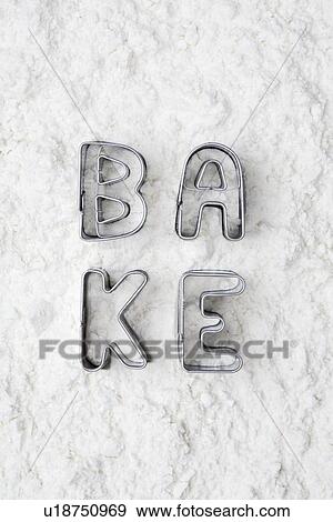 Stock Photo - Cookie cutters spelling bake in flour. Fotosearch