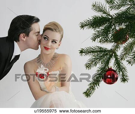 Stock Photography - Couple kissing by Christmas tree. Fotosearch