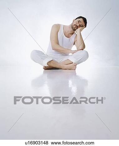 Stock Photo - Cross-legged man resting head in hands. Fotosearch
