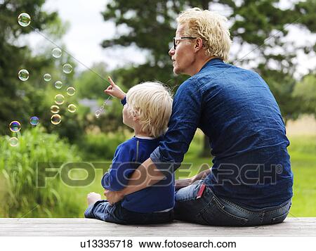 Father and son admiring bubbles outdoors View Large Photo Image Stock Photo - Father and son admiring bubbles outdoors. Fotosearch