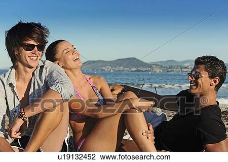 Friends laughing on rocky beach View Large Photo Image Stock Image - Friends laughing on rocky beach. Fotosearch