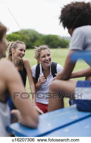 Stock Photograph - Friends talking on bleachers in park. Fotosearch