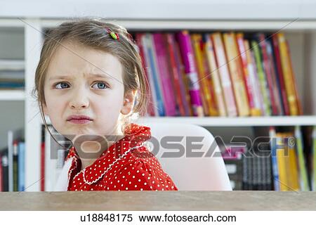 Frowning girl sitting at table View Large Photo Image Stock Photography - Frowning girl sitting at table. Fotosearch