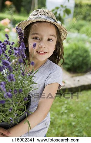 Stock Image - Girl carrying potted plants in backyard. Fotosearch