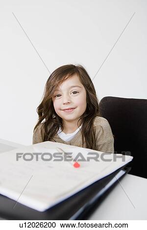 Stock Image - Girl doing her homework at desk. Fotosearch