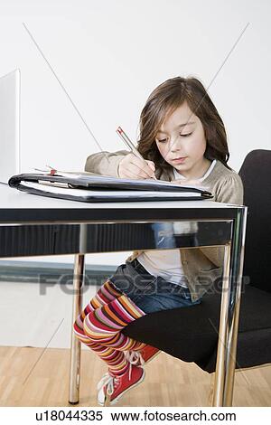 Girl doing her homework at desk View Large Photo Image Stock Photography - Girl doing her homework at desk. Fotosearch