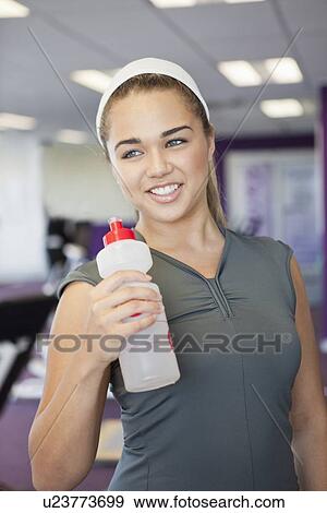 Stock Photo - Girl drinking water in gym. Fotosearch