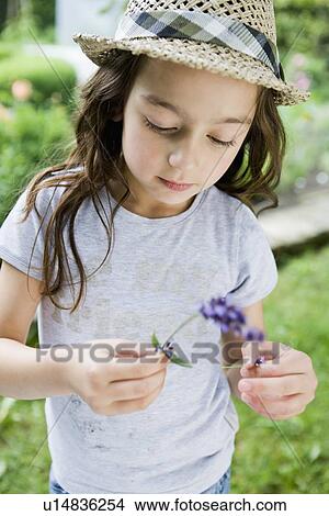 Picture - Girl examining flower outdoors. Fotosearch