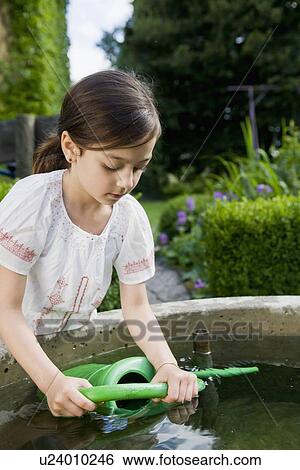 Girl filling up watering can in fountain View Large Photo Image Stock Photograph - Girl filling up watering can in fountain. Fotosearch
